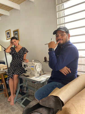 Gamelyn Oduardo and Karina Pacheco sitting in their leather workshop next to their juki sewing machine and rolled up hydes.Oduardo - handcrafted, small-batch, fair trade leather goods, husband and wife shop.