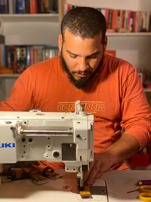 Gamelyn Oduardo is sewing part of a leather belt in our home leather workshop. Oduardo - handcrafted, small-batch, fair trade leather goods, husband and wife shop.