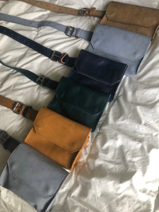 Beige, gray, blue, green and tan handmade genuine leather fanny pack (hipsack), can be used as a cross-body bag. Hand-crafted in Puerto Rico. Oduardo is a husband and wife leather goods handmade small-batch fair trade shop. We make all our products by hand. In our shop you can find convertible messenger bags, leather backpacks, leather briefcases, leather cross-body bags, leather passport covers, leather wallets, leather bifold wallets, and more!